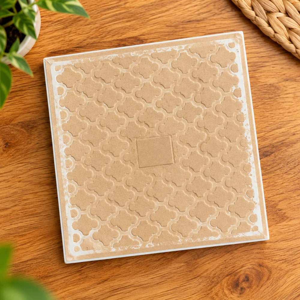 Vista posterior de cerámica sublimable cuadrada de 20 × 20 cm, con acabado beige texturizado sobre mesa de madera.